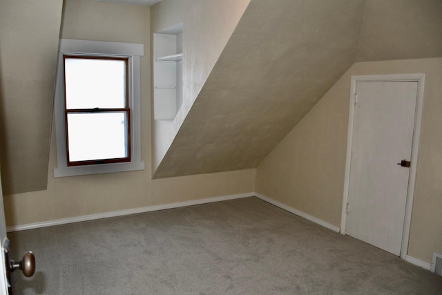 additional living space featuring lofted ceiling, light colored carpet, and built in features