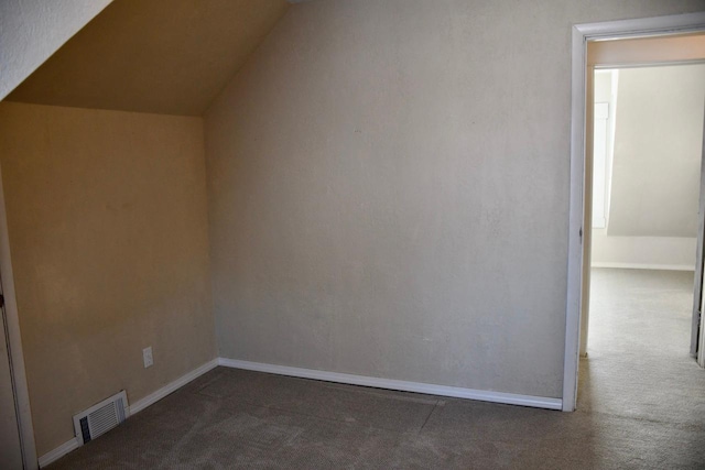 bonus room with vaulted ceiling and dark colored carpet