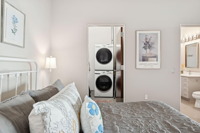 bedroom with ensuite bathroom, stacked washing maching and dryer, and sink