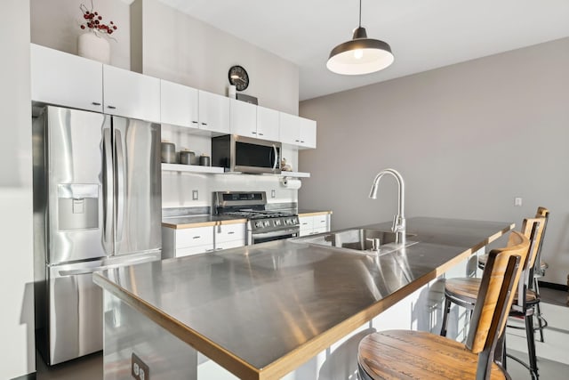 kitchen featuring sink, decorative light fixtures, a center island, stainless steel appliances, and white cabinets