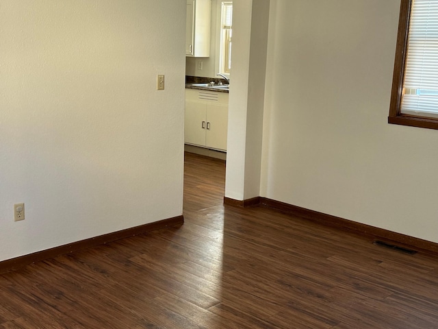 empty room with a healthy amount of sunlight, dark hardwood / wood-style flooring, and sink