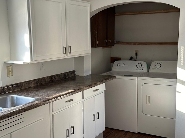 clothes washing area with cabinets, washing machine and clothes dryer, dark hardwood / wood-style floors, and sink