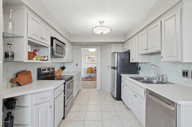 kitchen featuring sink, light tile patterned floors, stainless steel appliances, white cabinets, and a textured ceiling