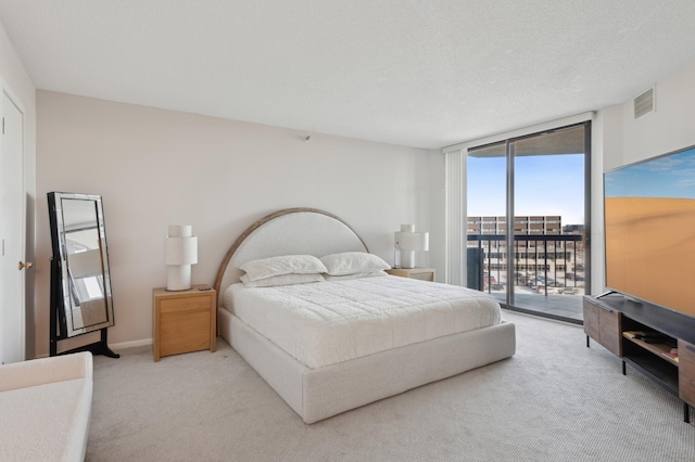 carpeted bedroom with expansive windows, a textured ceiling, and access to outside