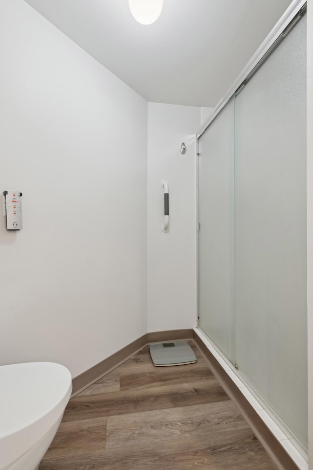 bathroom featuring walk in shower, toilet, and hardwood / wood-style floors