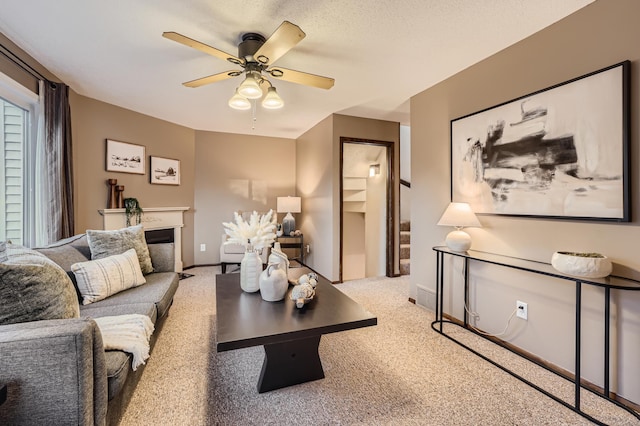 living room featuring ceiling fan, light colored carpet, a textured ceiling, and a fireplace