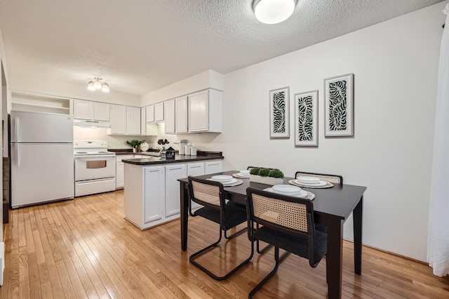 kitchen featuring white cabinetry, white appliances, light hardwood / wood-style flooring, and a textured ceiling