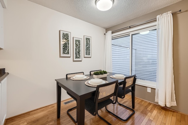 dining space featuring a textured ceiling and light wood-type flooring