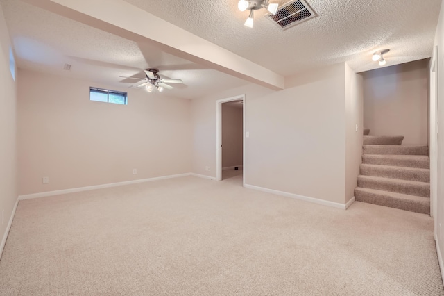 basement with ceiling fan, light carpet, and a textured ceiling