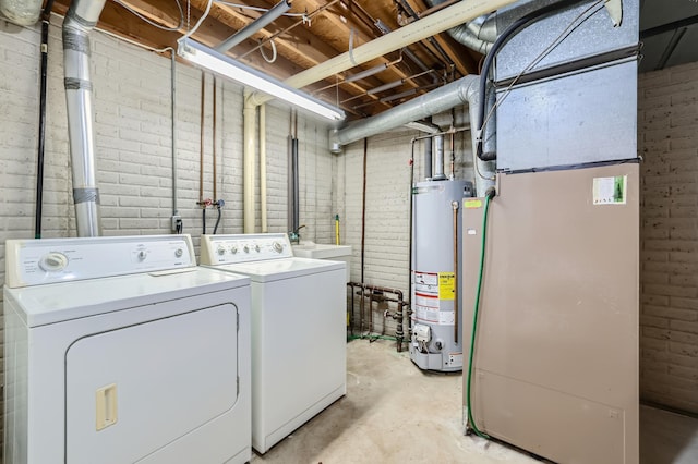 washroom with washing machine and clothes dryer, brick wall, and water heater