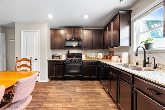 kitchen featuring sink, black appliances, light stone countertops, dark brown cabinets, and light hardwood / wood-style flooring