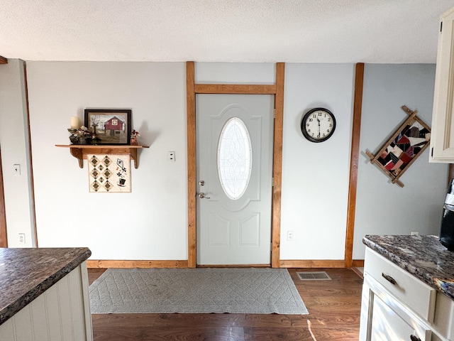 foyer with visible vents, baseboards, a textured ceiling, and dark wood-style flooring