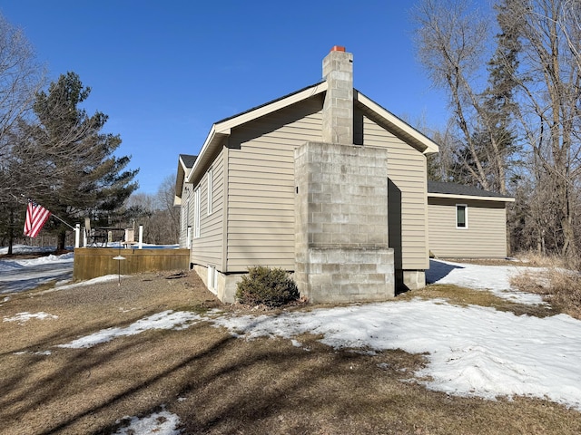 view of snow covered exterior with a chimney