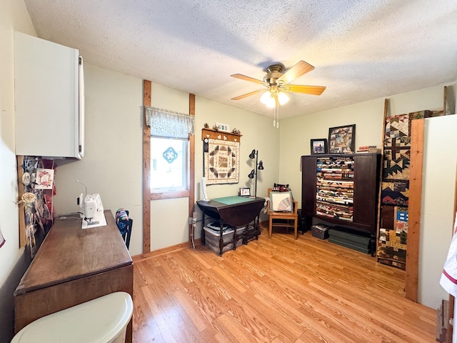 office area featuring light wood-style floors, ceiling fan, and a textured ceiling