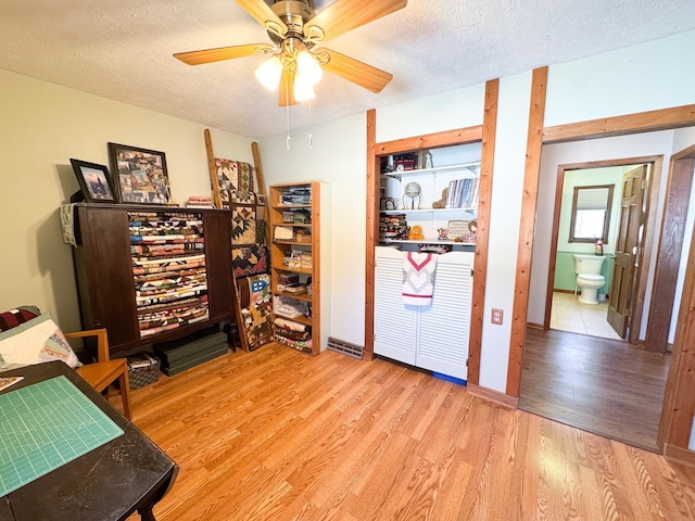 office area with a ceiling fan, wood finished floors, and a textured ceiling