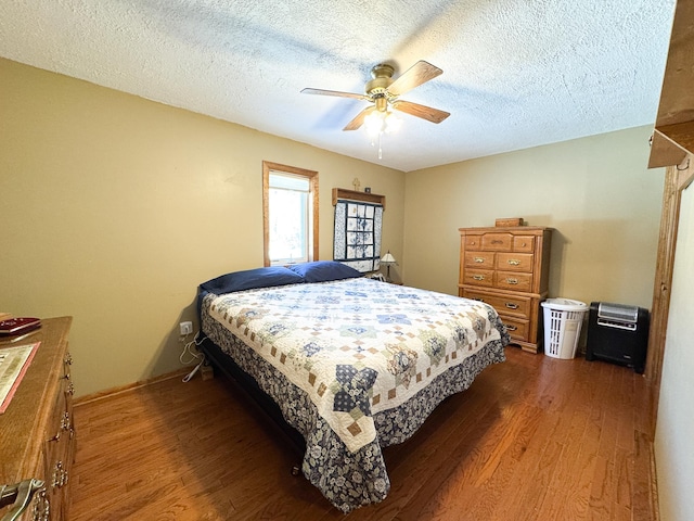 bedroom featuring baseboards, a textured ceiling, a ceiling fan, and wood finished floors