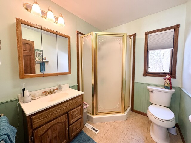 bathroom with tile patterned flooring, a wainscoted wall, toilet, a stall shower, and vanity