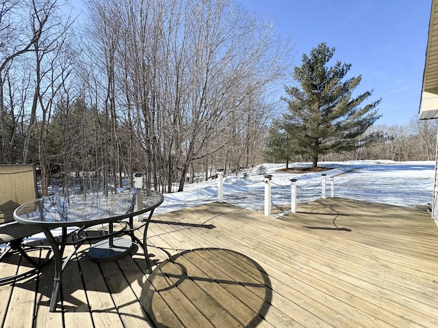 snow covered deck featuring outdoor dining space and a boat dock