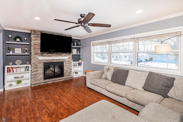 living room featuring a stone fireplace, built in features, dark hardwood / wood-style flooring, ornamental molding, and ceiling fan