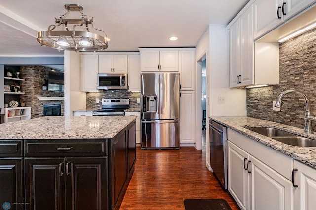 kitchen featuring stainless steel appliances, a center island, sink, and white cabinets