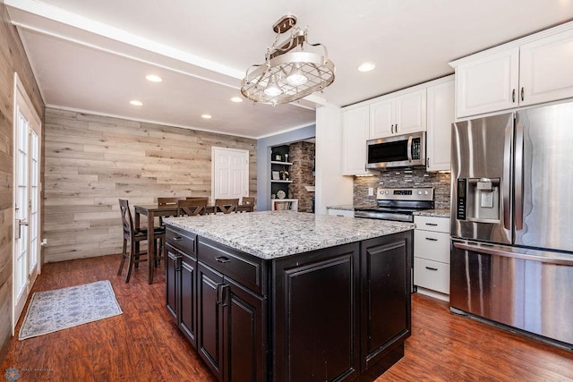 kitchen featuring appliances with stainless steel finishes, white cabinetry, a kitchen island, dark hardwood / wood-style flooring, and decorative light fixtures