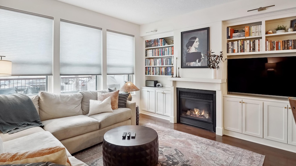 living room with dark hardwood / wood-style floors, a textured ceiling, and built in shelves