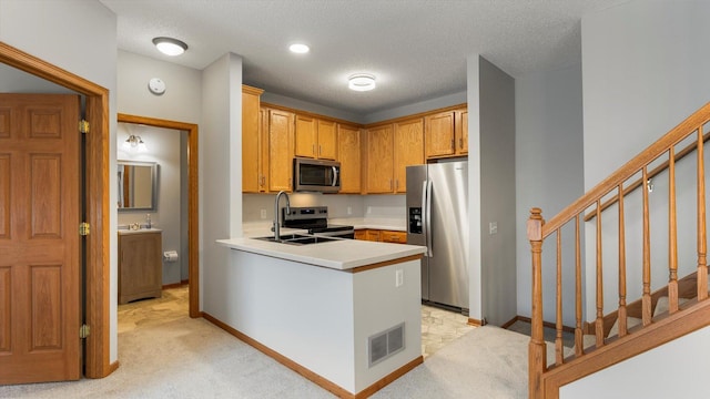 kitchen featuring appliances with stainless steel finishes, light carpet, a textured ceiling, and kitchen peninsula