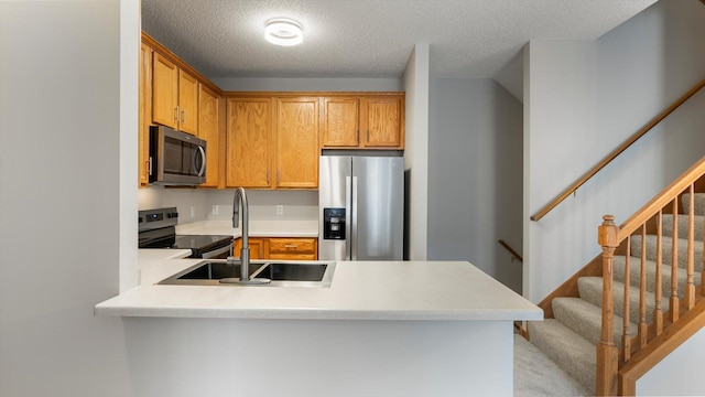 kitchen with stainless steel appliances, sink, a textured ceiling, and kitchen peninsula