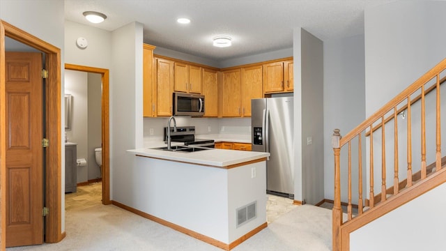 kitchen featuring appliances with stainless steel finishes, sink, light carpet, and a textured ceiling