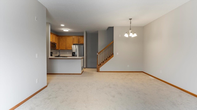 unfurnished living room featuring sink, light colored carpet, and an inviting chandelier