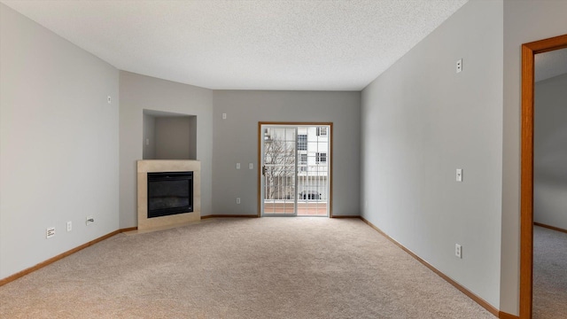 unfurnished living room featuring a tile fireplace, light carpet, and a textured ceiling