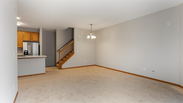 carpeted spare room featuring an inviting chandelier