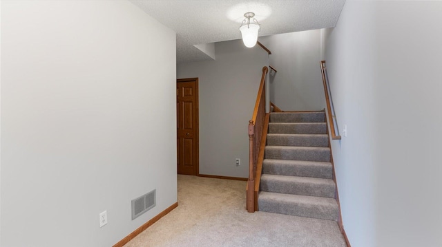 staircase with carpet flooring and a textured ceiling