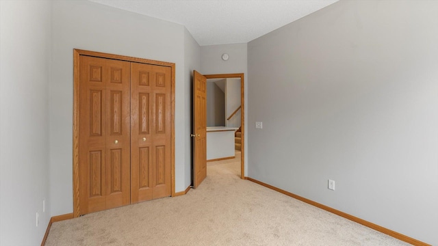 unfurnished bedroom with light colored carpet and a closet