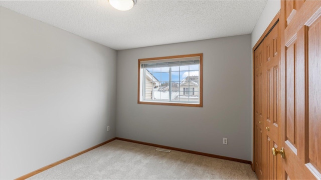 carpeted spare room with a textured ceiling