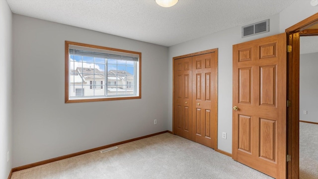 unfurnished bedroom featuring light colored carpet and a textured ceiling