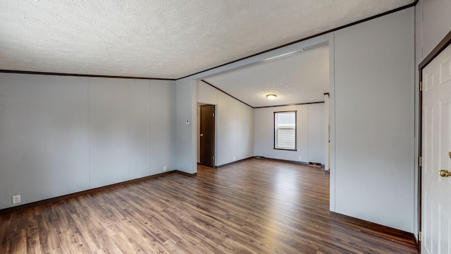 unfurnished room with dark hardwood / wood-style flooring, vaulted ceiling, ornamental molding, and a textured ceiling