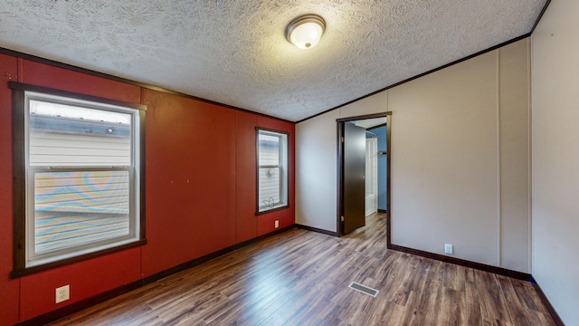 empty room with hardwood / wood-style flooring, a healthy amount of sunlight, lofted ceiling, and a textured ceiling