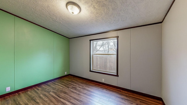 empty room with dark wood-type flooring, ornamental molding, and a textured ceiling