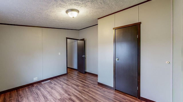 unfurnished bedroom featuring crown molding, wood-type flooring, and a textured ceiling