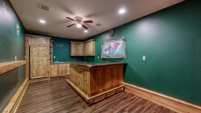 kitchen featuring light brown cabinetry, a kitchen breakfast bar, dark hardwood / wood-style flooring, ceiling fan, and kitchen peninsula