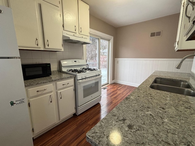 kitchen with dark hardwood / wood-style floors, sink, light stone counters, and white appliances