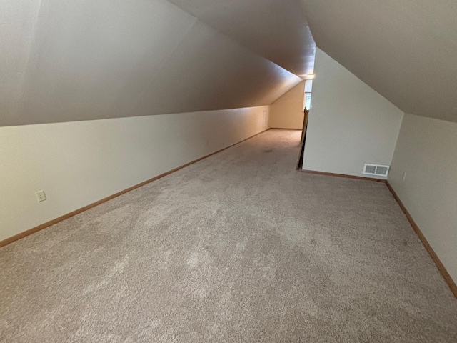 bonus room with lofted ceiling and light carpet