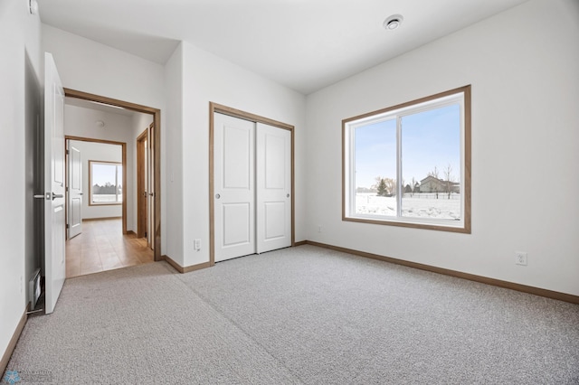 unfurnished bedroom with light carpet and a closet