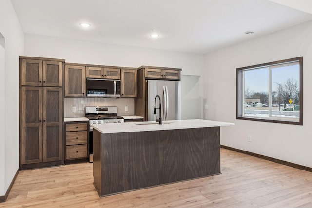 kitchen with light hardwood / wood-style flooring, sink, a center island with sink, and appliances with stainless steel finishes