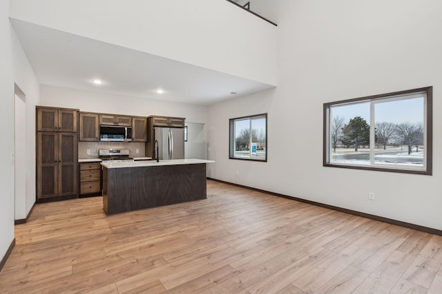 kitchen with light hardwood / wood-style floors, stainless steel appliances, a center island, and a healthy amount of sunlight