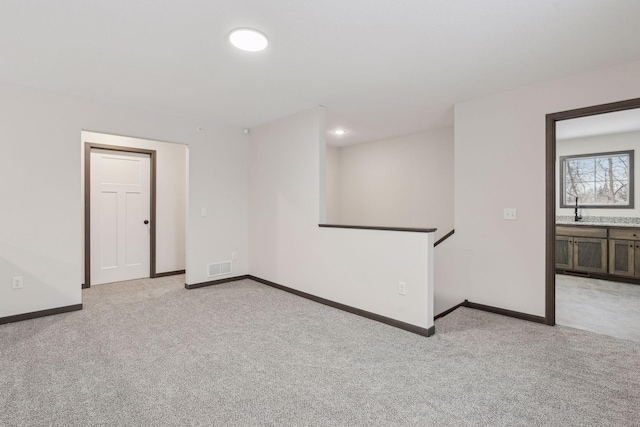 spare room featuring sink and light carpet