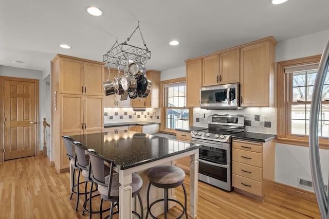 kitchen with appliances with stainless steel finishes, a center island, light hardwood / wood-style flooring, and light brown cabinets