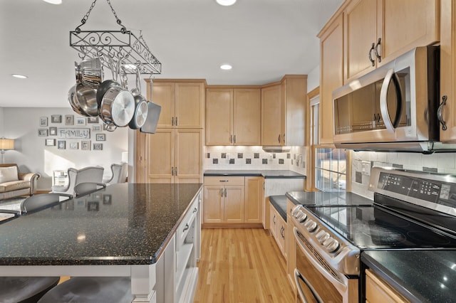 kitchen featuring light hardwood / wood-style flooring, appliances with stainless steel finishes, hanging light fixtures, a center island, and light brown cabinetry