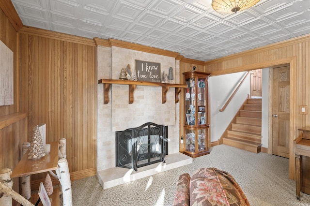 living room with crown molding, a fireplace, wooden walls, and light carpet